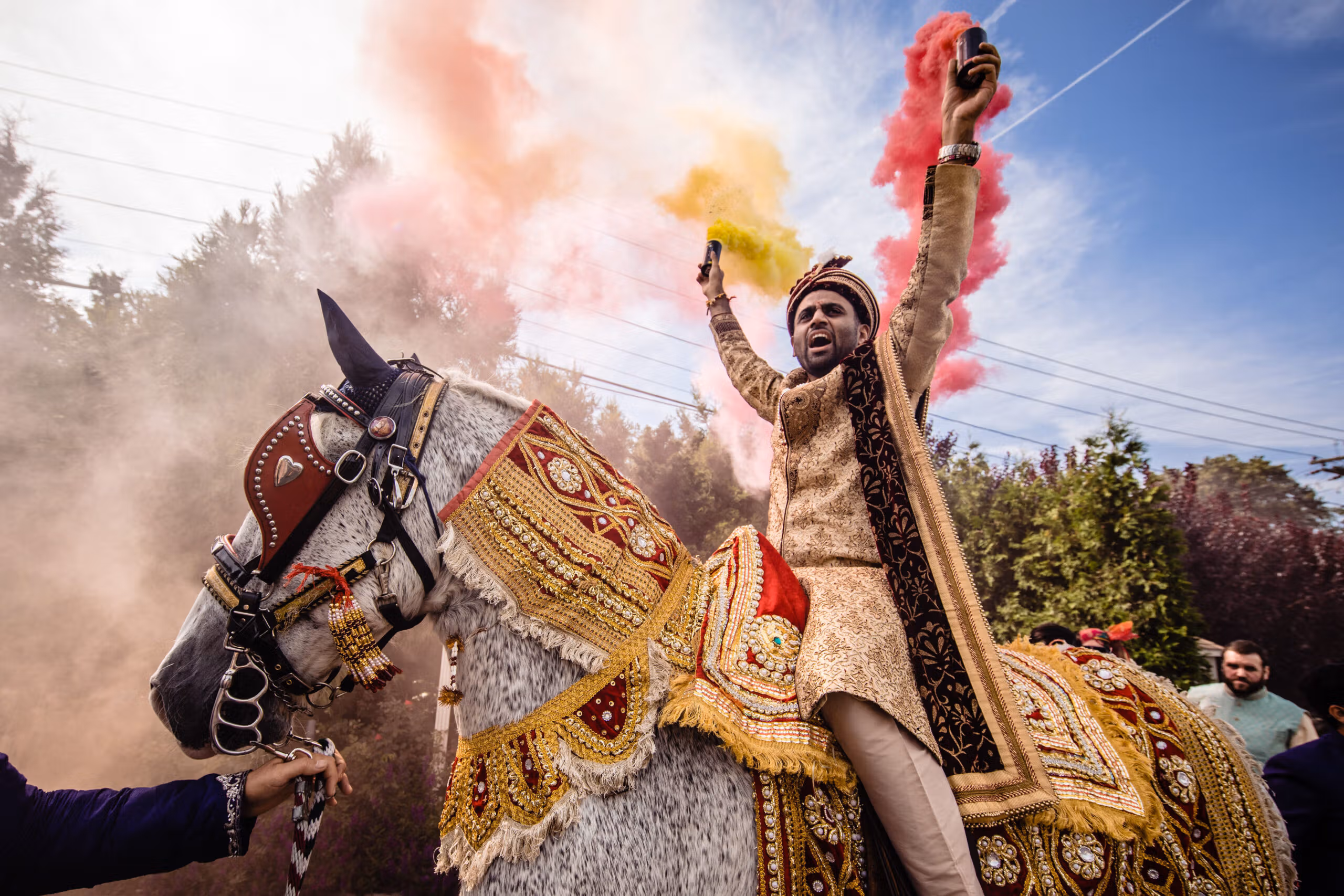 Groom celebrating on horseback amid colourful powder during a Baraat