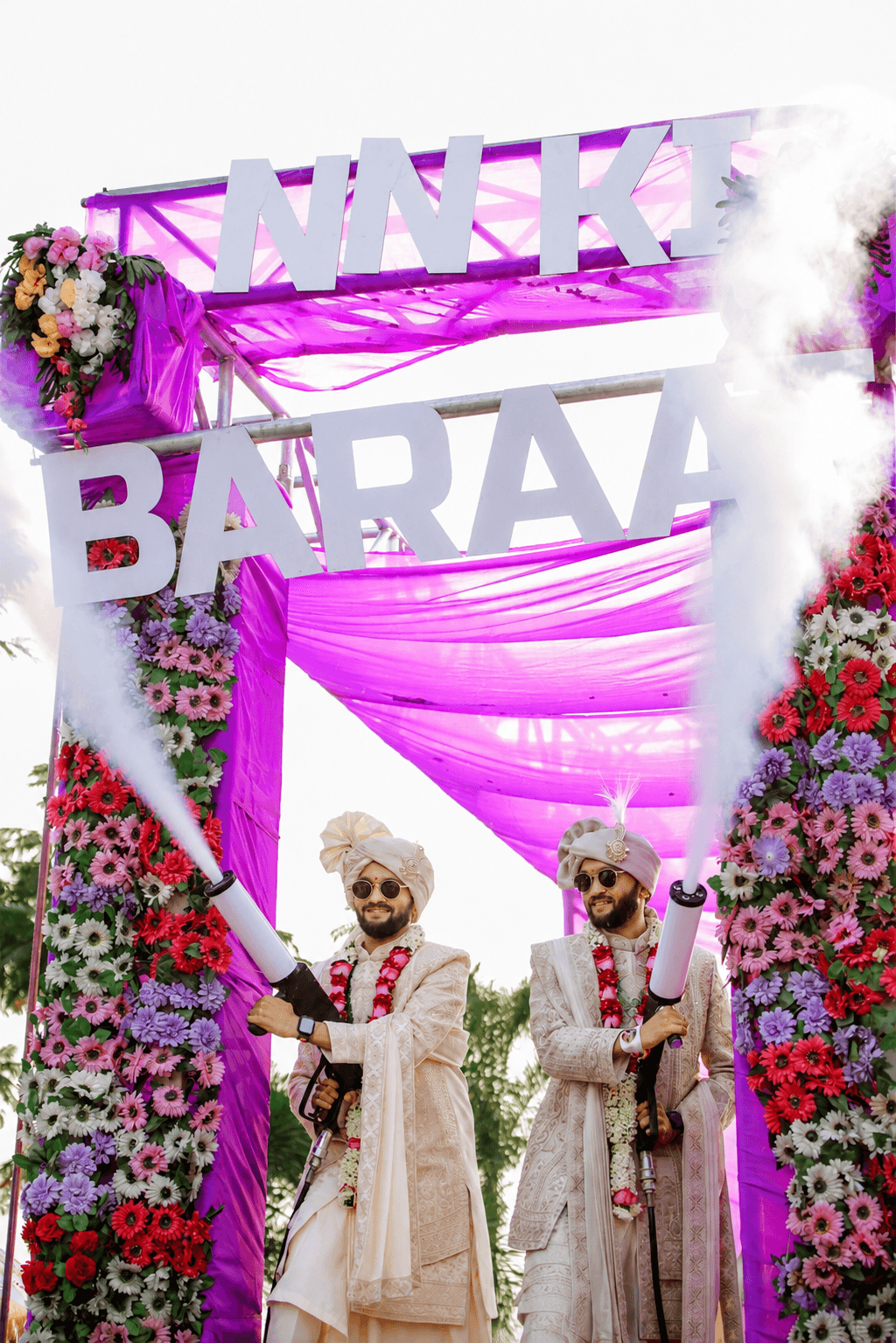 A coordinated couple moment beside a personalised Baraat installation